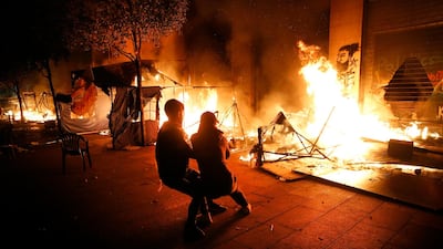 Anti-government protesters try to extinguish their tents which were set on fire in Beirut. AP Photo