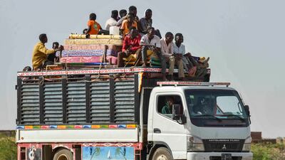 People ride with furniture and other items on a lorry moving along a road from Khartoum to Wad Madani. AFP