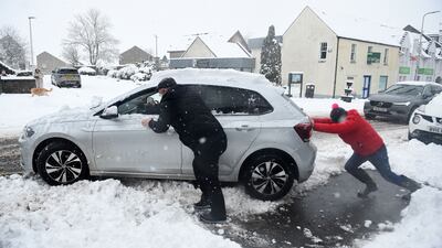 People push a car out of the snow in Auchterarder, central Scotland. AFP