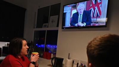 A family gather around the television in Liverpool to watch Britain's Prime Minister Boris Johnson give a televised message. AFP