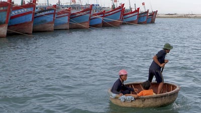 Nguyen Hap, right, paddles a boat to transport Bui Van Minh, left, and his son Bui Van Chau to Minh’s damaged fishing boat at a quay of Ly Son port. Kham / Reuters