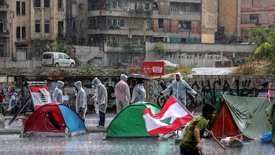 A protester carry Lebanese flag run during rain as protesters close the Achrafieh highway. EPA