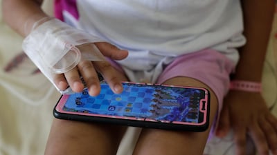 A young dengue patient plays on a smartphone at the San Lazaro government hospital in Manila.