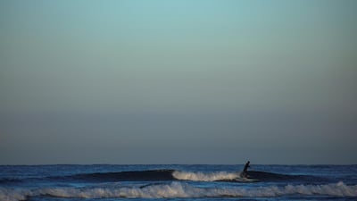 A surfer rides a wave as the moon sets and the sun rises at Cardiff State Beach in Encinitas, California. Reuters