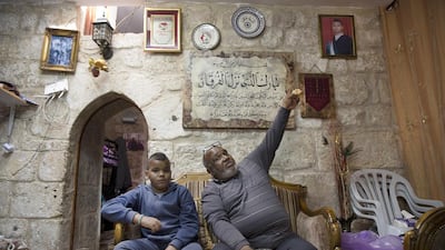 Afro-Palestinian Shahlin Husani with his son Muron, 8, on March 4, 2016. Shahin points to a photograph of his relative Ossama Jebdeh, 23, whom he claims was one of the first killed by Israeli troops during the second Intifada when he was trying to reach a hospital to donate blood. Shahlin and his family live in the African Muslim Community nearby the Al Aqsa Mosque in the Old City of Jerusalem.