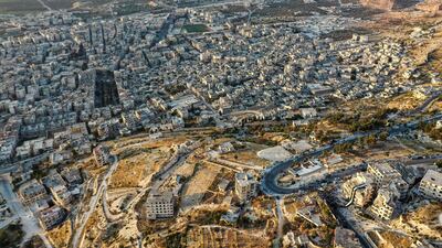 Syrians gathering for a demonstration by the ruins of a building that was hit in the prior bombardment and adorned with a giant flag of the Syrian opposition, in the town of Ariha in the rebel-held northwestern Idlib province. AFP