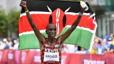 Eliud Kipchoge celebrates with the Kenyan national flag after winning the men's marathon.