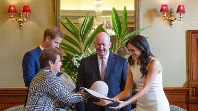 Prince Harry and his Meghan look at bush hats with Australia's Governor General Peter Cosgrove and his wife. AP Photo