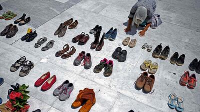 A woman prays in front of hundreds of shoes that were displayed in memory of those killed by Hurricane Maria in front of the Puerto Rican Capitol, in San Juan. AFP/Ricardo ARDUENGO