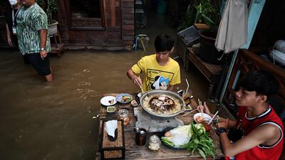 People eat dinner in a Bangkok restaurant as flood water from Thailand's Chao Phraya River surges in. AFP