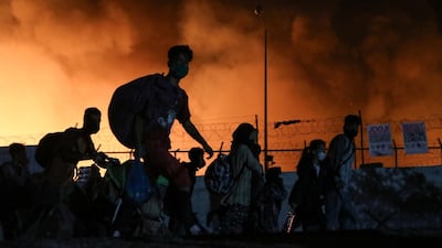 Refugees carry their belongings as they flee from a fire burning at the Moria camp, on the island of Lesbos, Greece. Reuters
