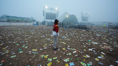 A man stands in a field covered in litter ahead of the clean up operation at the end of the Glastonbury Festival at Worthy Farm in Somerset. PA
