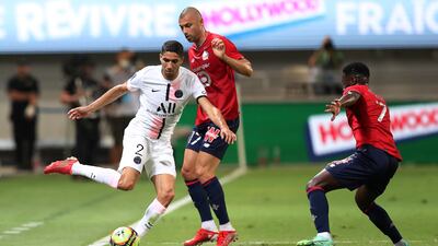 PSG's Achraf Hakimi, left, tries to dribble past Lille's Burak Yilmaz.