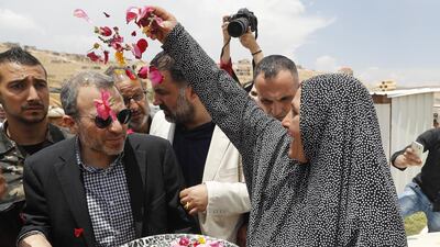 A Syrian refugee woman throws flowers on Lebanese Foreign Minister Gebran Bassil, centre, during his visit a Syrian refugee camp, in Arsal, near the border with Syria, east Lebanon, Wednesday, June 13, 2018. (AP Photo/Hussein Malla)