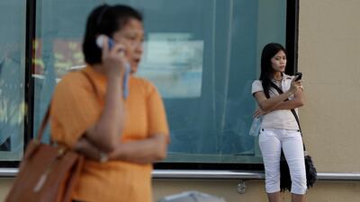 Women use cell phone or mobile phone near Al Wahda Mall in Abu Dhabi. Ryan Carter / The National