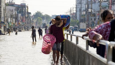 A man carries cats to safety across a flooded street in Wellampitiya, Sri Lanka. Reuters