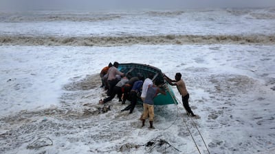 People try to move a fishing boat to a safer ground on the Arabian Sea coast in Veraval, Gujarat, India. AP Photo