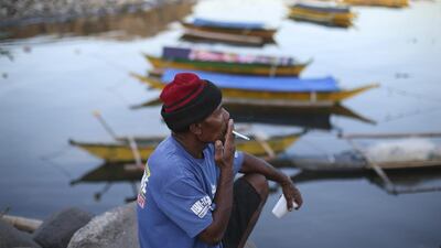 Filipino fisherman Elijio Ortillada, 54, smokes a cigarette as he takes a break from making fishing nets in Manila Bay, Philippines. Aaron Favila / AP Photo