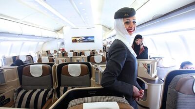 An Etihad flight attendant welcomes passengers on to an Etihad aircraft. The carrier is seeking apartments as it expands its staff. Sammy Dallal / The National