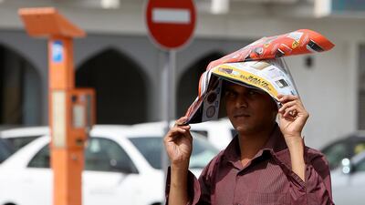 Man covering himself with a magazine to avoid heat stroke from the intense summer sun at Karama in Dubai. Pawan Singh / The National