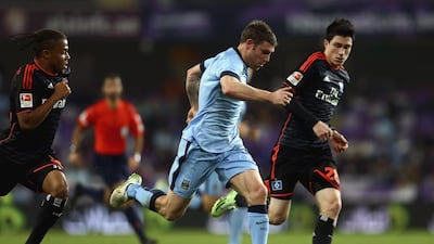 James Milner, centre, of Manchester City gets a step on Hamburg’s Mende Sven on Wednesday night at the Hazza bin Zayed Stadium in Al Ain. Francois Nel / Getty Images