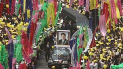 A huge portrait of Roh Moo-hyun, the late former South Korean president, leads the funeral hearse as it makes through a mammoth crowd.