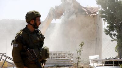 An Israeli soldier stands guard as the restaurant is flattened. EPA