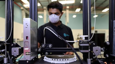 Karteek Raghu, operations manager at the lab uses a 3D printer to make the structure of a 3D face mask. Pawan Singh / The National