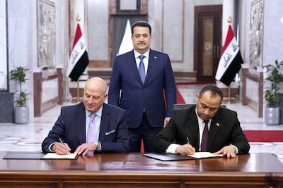 Iraqi Prime Minister Mohammed Shia Al Sudani looks on as George Pickart of US electrical services company GE Vernova, left, and Iraq's Electricity Minister Ziad Ali Fadel sign a memorandum of understanding in Baghdad. AFP