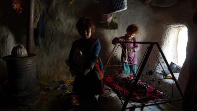 Internally displaced Afghan children play inside a mud shelter at a makeshift camp as winter approaches in Kabul. Shah Marai / AFP Photo