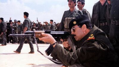 Saddam Hussein points a Kalashnikov at an unspecified location in Iraq, 1987. AFP