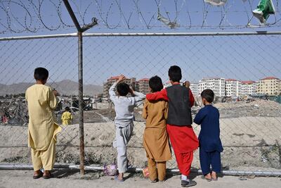 Children watch people at a camp for internally displaced people in Kabul on June 21. AFP