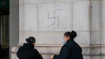 A cleaning crew prepares to cover hand-drawn swastikas. AP