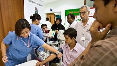 Johanna Buenviaje takes the blood pressure of Abdul Momin, 25, as his friend Faruk, 20, watches during a free public health awareness screening at Dubai's Rashid Hospital for World Heart Day yesterday.