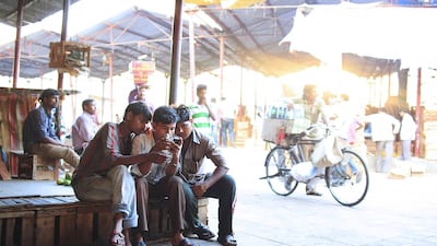 People check out television content on as smartphone at a market in Mumbai. Subhash Sharma / The National