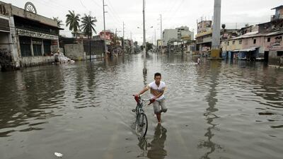 A Filipino pushes his bike in a flooded street in Manila, Philippines. Ritchie B Tongo/EPA