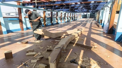A worker chips away at some wood to repair part of the dhow, which needs occasional maintenance because it is completely handmade. Antonie Robertson / The National