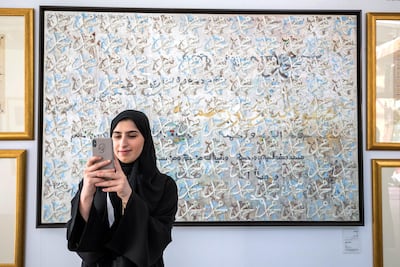 Visitor takes a selfie in front of artwork at the Al Burda Festival, Abu Dhabi. Leslie Pableo for The National