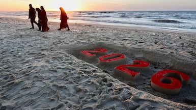 Palestinians walk past a sand sculpture reading "2026" on the beach in Gaza City on New Year's Eve on December 31, 2025. The United Nations rights chief described on December 31 Israel's threat to suspend dozens of aid groups from operating in Gaza from January as "outrageous", calling on states to urgently insist Israel shift course. AFP