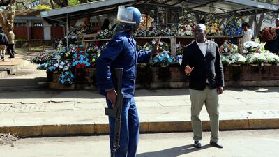 An armed riot policeman gestures to a pedestrian. AP Photo
