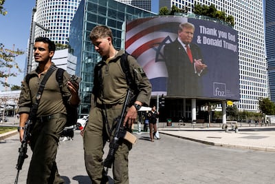 Israeli soldiers walk by a billboard displaying a picture of US President Donald Trump with the words "Thank you God & Donald Trump" in Tel Aviv. Reuters