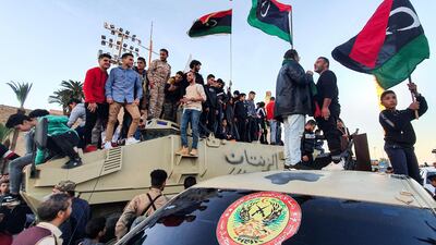 People stand with Libyan national flags above armoured military vehicles of forces loyal to the UN-recognised Tripoli-based "Government of National Accord" (GNA) during a celebration in the capital's Martyrs' Square. AFP