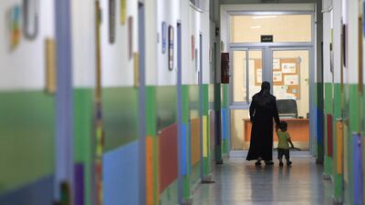 A woman walks with her child in the corridor of a school housing families displaced from the south of Lebanon. AFP