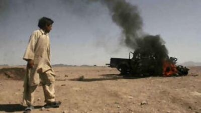 An Afghan boy look at police vehicle set on fire by protesters during a demonstration against the killing of civilian in an airstrike in Azizabad the village in Shindand district of Herat province, Afghanistan, Saturday, Aug 23, 2008. The U.S.-led coalition said Saturday that it would investigate allegations of civilian deaths during the battle.
