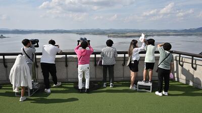 Visitors use binoculars to look at the North Korean side of the Demilitarised Zone (DMZ) dividing the two Koreas, from South Korea's Odusan Unification Observatory in Paju on October 9, 2024. North Korea's army said on October 9 it was moving to "permanently shut off and block the southern border" with Seoul and had informed the US military to prevent an accidental clash. (Photo by Jung Yeon-je / AFP)