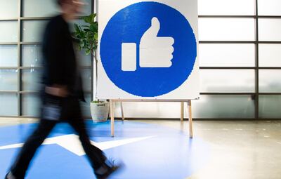 A Facebook employee walks by a sign displaying the "like" sign at Facebook's corporate headquarters campus in Menlo Park, California. AFP