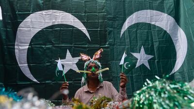 A street vendor holds Pakistani national flags as he waits for customers at a market in Lahore. AFP