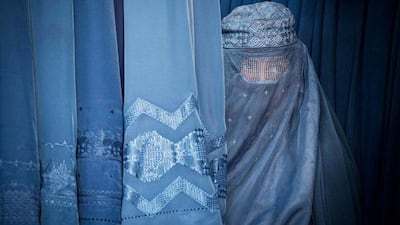 An Afghan woman peers through the the eye slit of her burqa as she waits to try on a new burqa in shop in the old town of Kabul, Afghanistan.