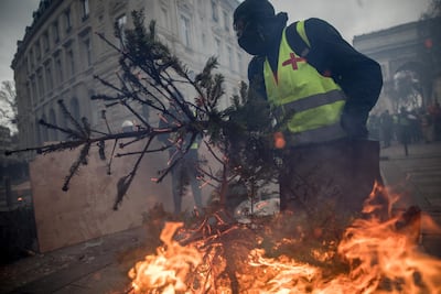 A protester carries a burning Christmas tree to a barricade during the 'yellow vests' demonstration near the Arc de Triomphe. Getty Images