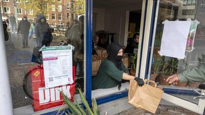 A volunteer from the Samen Sterk Vrouwen West foundation hands out a meal in Amsterdam, The Netherlands. EPA
